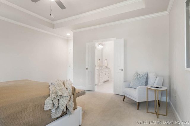 bedroom featuring ensuite bathroom, light carpet, baseboards, a raised ceiling, and crown molding