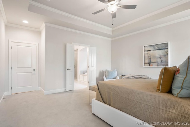 bedroom featuring baseboards, a raised ceiling, light colored carpet, ensuite bathroom, and crown molding