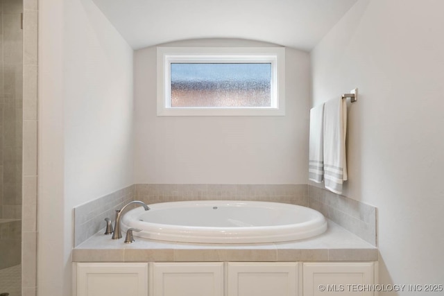 bathroom with a garden tub and a tile shower