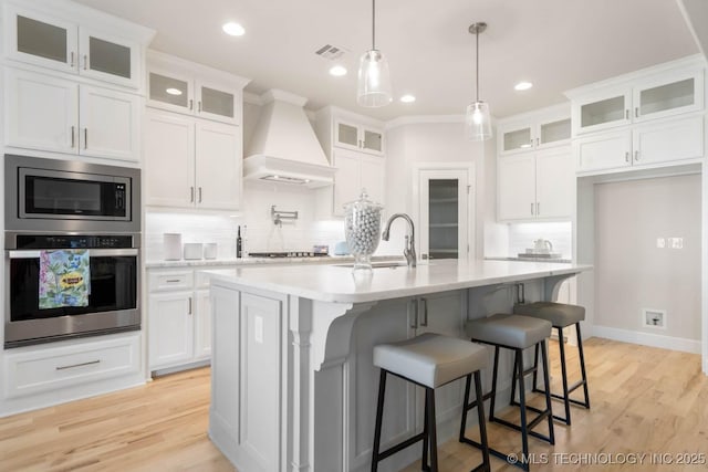 kitchen featuring stainless steel appliances, premium range hood, a sink, and light countertops