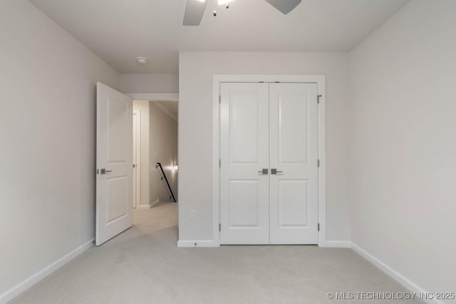 unfurnished bedroom with ceiling fan, baseboards, a closet, and light colored carpet