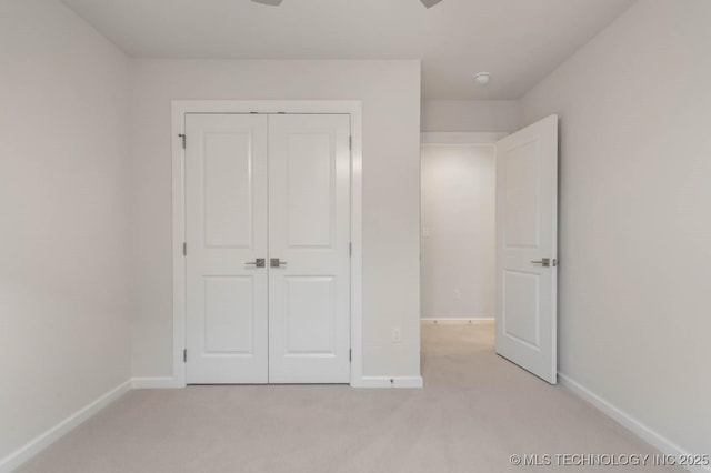 unfurnished bedroom with baseboards, a closet, and light colored carpet