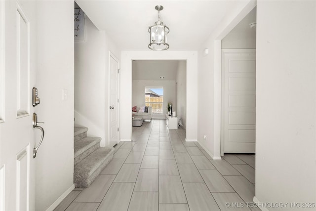 hall with a notable chandelier, baseboards, and stairs