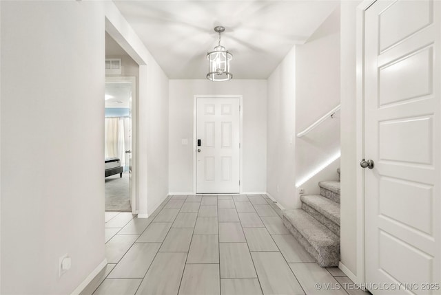 foyer with a notable chandelier, stairway, visible vents, and baseboards