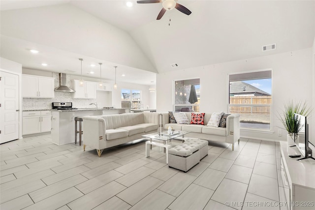 living area featuring high vaulted ceiling, a wealth of natural light, visible vents, and a ceiling fan