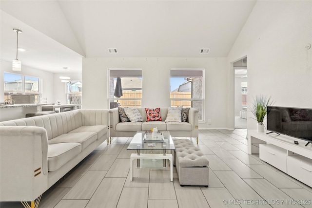 living area with high vaulted ceiling, baseboards, and visible vents