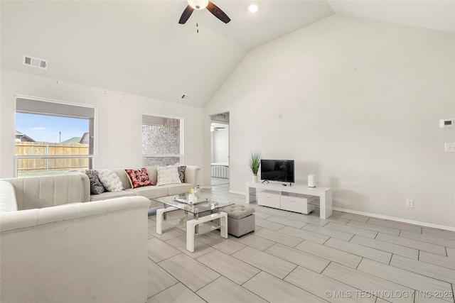 living area with high vaulted ceiling, ceiling fan, visible vents, and baseboards