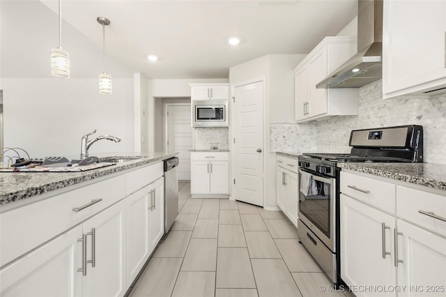 kitchen featuring stainless steel appliances, white cabinetry, wall chimney range hood, and tasteful backsplash