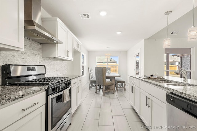 kitchen with wall chimney exhaust hood, visible vents, stainless steel appliances, and a sink