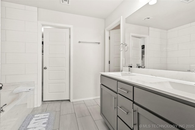 bathroom featuring double vanity, a bathtub, visible vents, and a sink