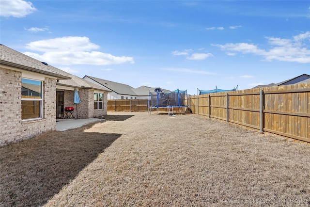 view of yard with a fenced backyard, a trampoline, and a patio