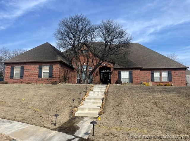 view of front of house featuring brick siding and a shingled roof