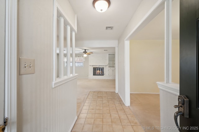 hallway with light tile patterned flooring, visible vents, and light colored carpet