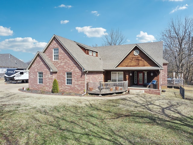 back of house featuring roof with shingles, fence, a lawn, and brick siding