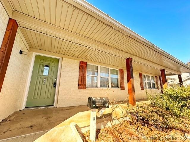 entrance to property with covered porch and brick siding