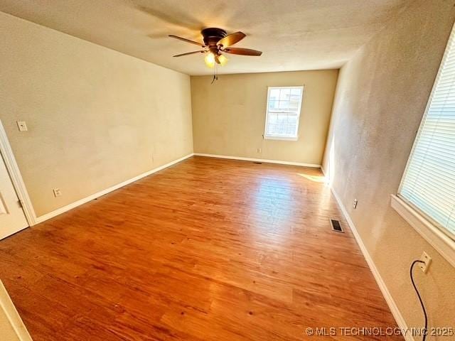 unfurnished room with visible vents, ceiling fan, baseboards, and wood finished floors