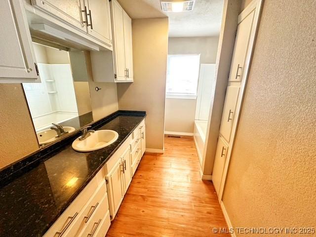 full bath featuring vanity, wood finished floors, visible vents, and baseboards