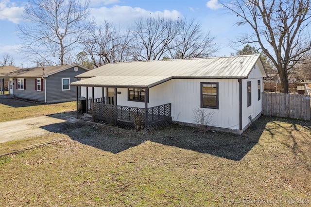 view of front facade featuring covered porch, fence, and metal roof