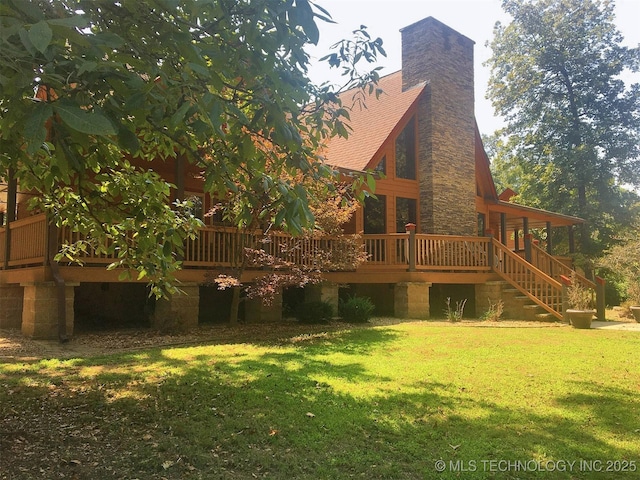 back of property featuring a shingled roof, a chimney, a yard, stairs, and a wooden deck