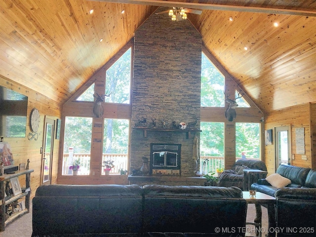 living room featuring wooden walls, wooden ceiling, a healthy amount of sunlight, and a stone fireplace