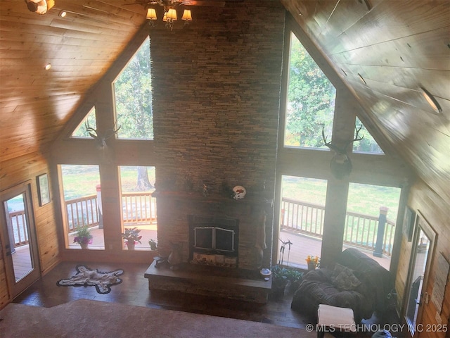 living area with a fireplace with raised hearth, wooden walls, wood finished floors, high vaulted ceiling, and wooden ceiling