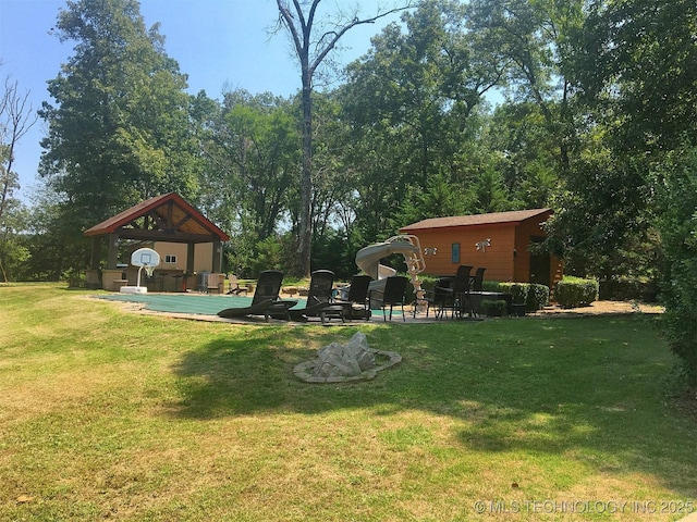 view of yard featuring a patio area, a pool, and an outdoor structure