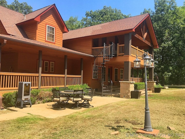 back of property featuring a patio, a shingled roof, and a lawn