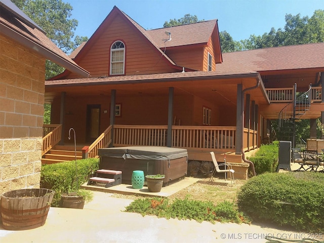 back of property featuring a patio area, a hot tub, and a shingled roof