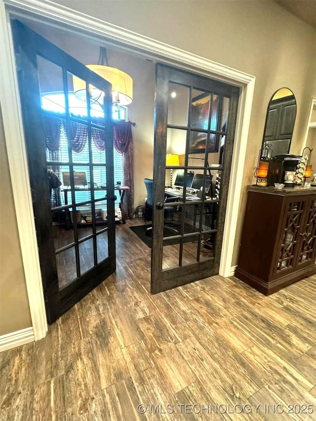 interior space with baseboards, wood finished floors, and french doors