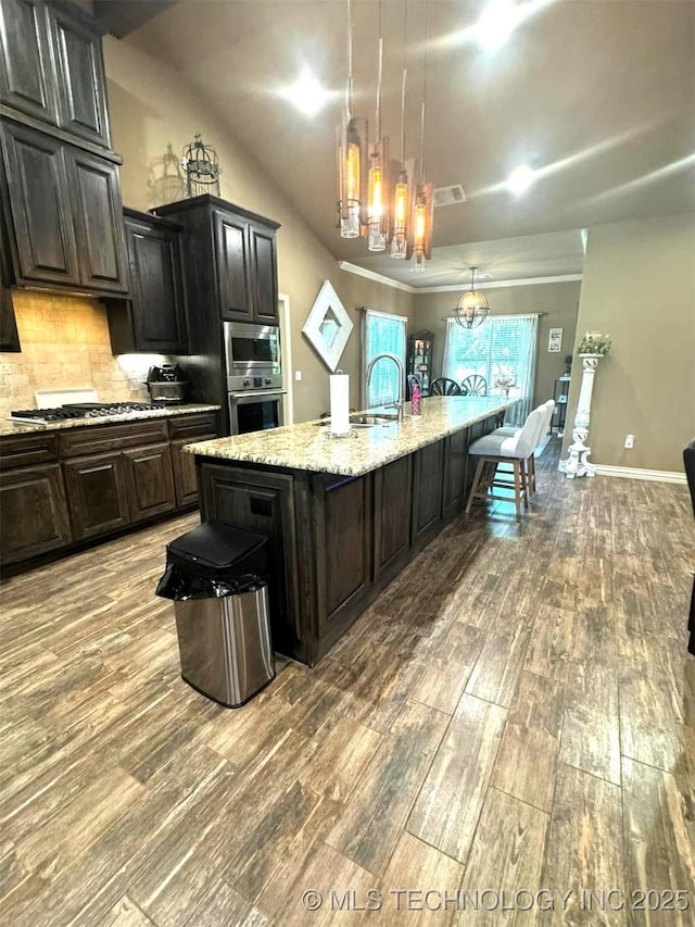 17 Tabernacle Dr, Calera, OK 74730 - kitchen with a notable chandelier, appliances with stainless steel finishes, wood finished floors, backsplash, and a large island with sink