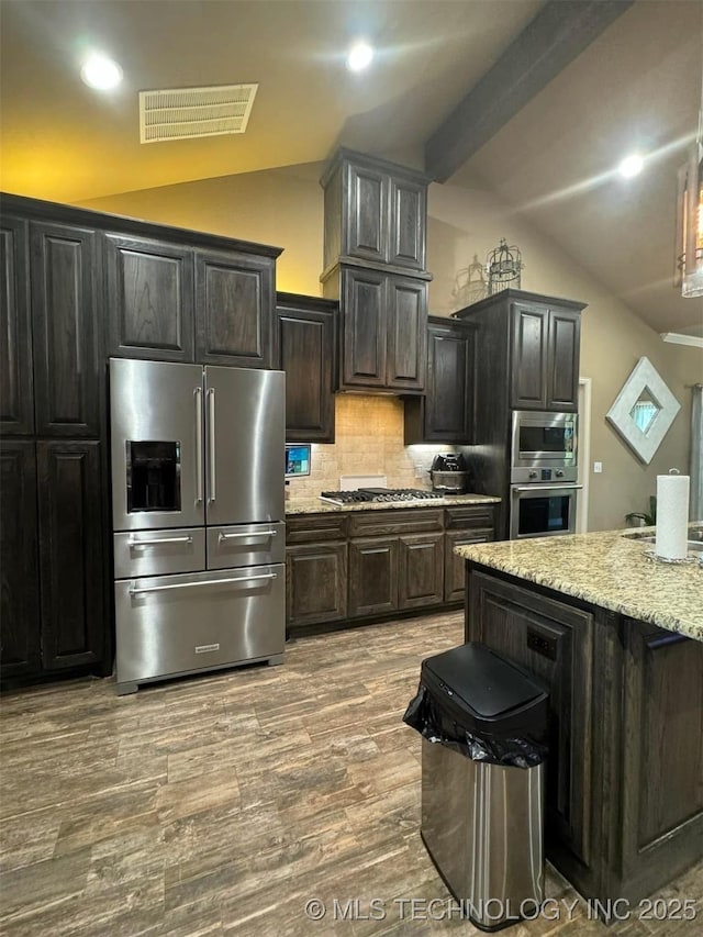 17 Tabernacle Dr, Calera, OK 74730 - kitchen with wood finished floors, visible vents, appliances with stainless steel finishes, vaulted ceiling, and tasteful backsplash