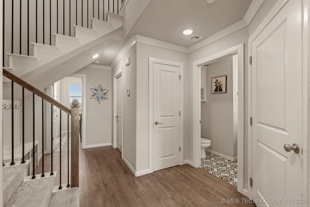 corridor featuring stairway, baseboards, crown molding, and wood finished floors