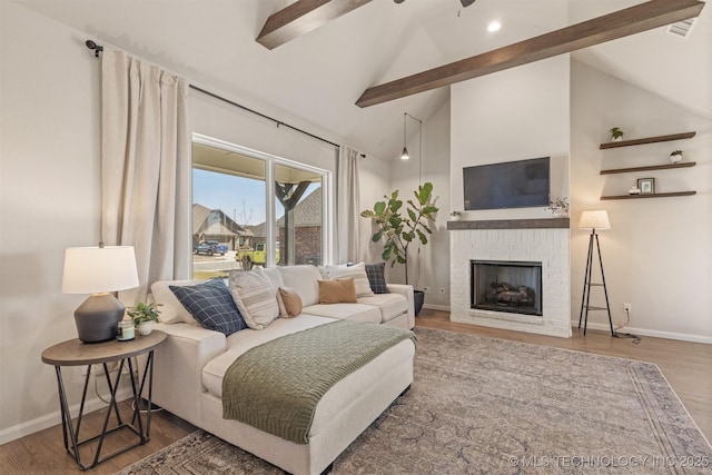 living room with visible vents, beamed ceiling, wood finished floors, a fireplace, and high vaulted ceiling