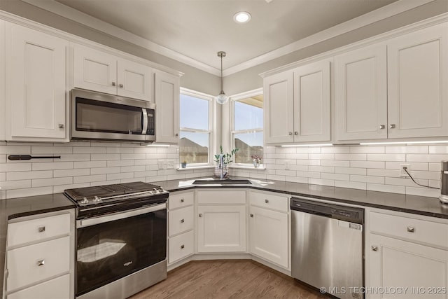 kitchen featuring dark countertops, white cabinetry, stainless steel appliances, and a sink