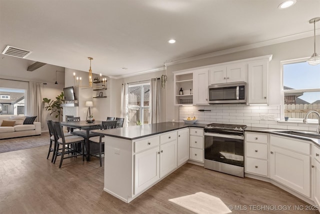 kitchen with stainless steel appliances, dark countertops, a peninsula, and decorative backsplash