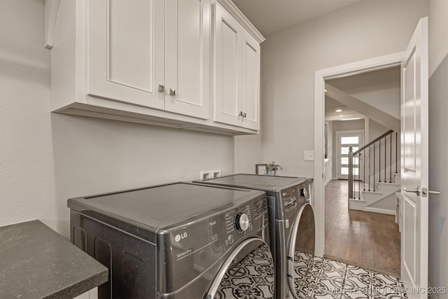 laundry room with light wood-type flooring, washing machine and clothes dryer, cabinet space, and baseboards