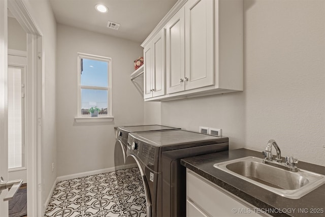 laundry area with cabinet space, visible vents, baseboards, washing machine and dryer, and a sink