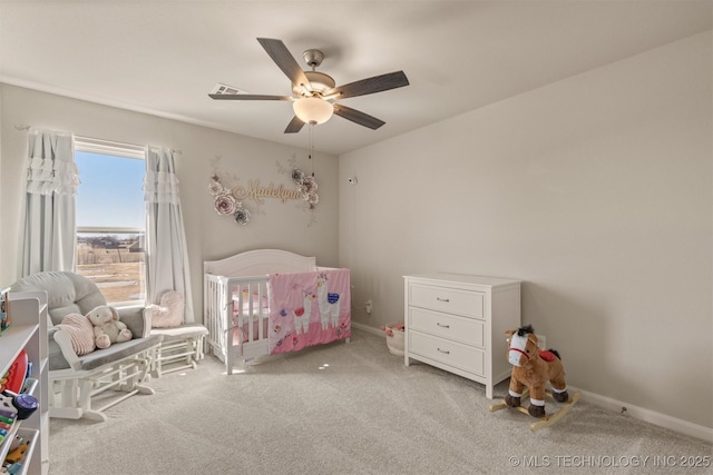 carpeted bedroom featuring a ceiling fan, a nursery area, and baseboards