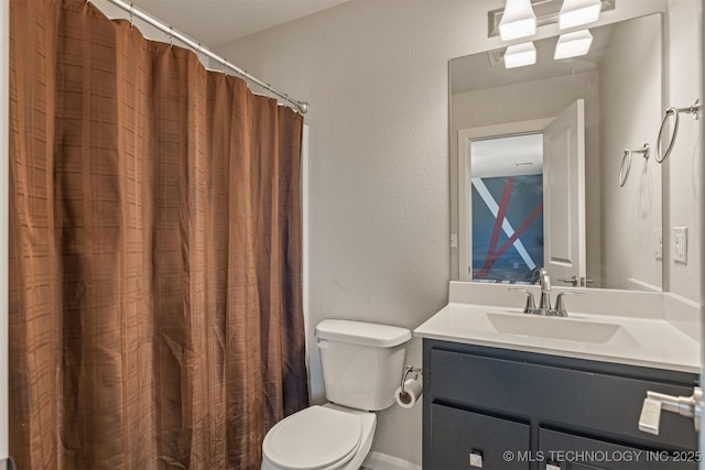 full bath featuring toilet, a textured wall, and vanity