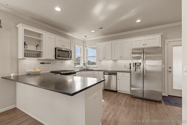 kitchen featuring visible vents, dark countertops, wood finished floors, a peninsula, and stainless steel appliances