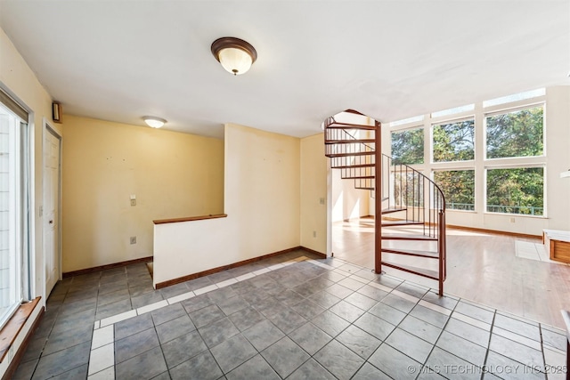 empty room featuring stairs, tile patterned flooring, and baseboards