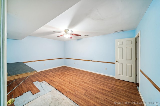 empty room featuring ceiling fan, wood finished floors, visible vents, and baseboards