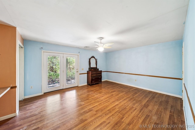 empty room featuring a ceiling fan, baseboards, and wood finished floors