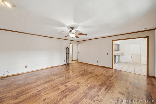 empty room with baseboards, a ceiling fan, light wood-style flooring, and crown molding