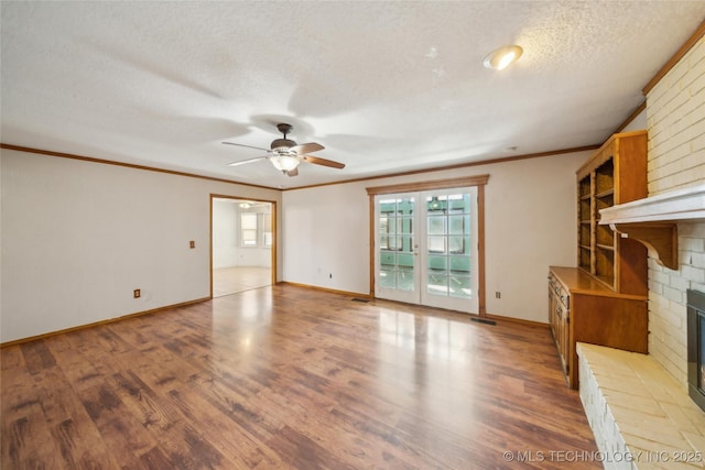 unfurnished living room featuring crown molding, a fireplace, a textured ceiling, and wood finished floors