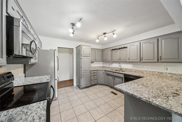 kitchen featuring light tile patterned floors, gray cabinetry, a sink, black appliances, and tasteful backsplash