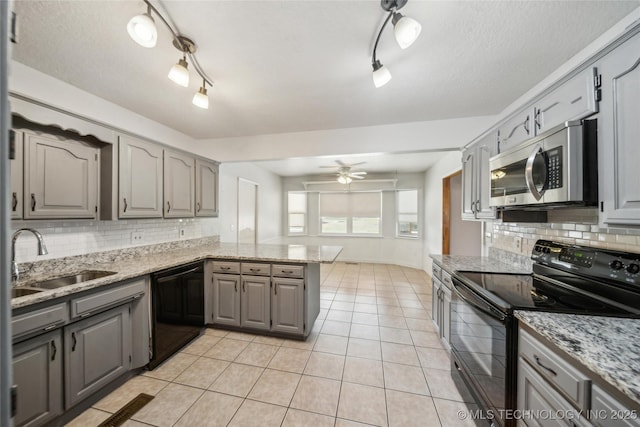 kitchen with a peninsula, gray cabinetry, black appliances, a sink, and light tile patterned flooring