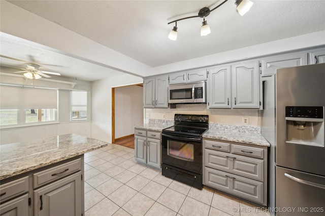 kitchen featuring stainless steel appliances, light tile patterned floors, gray cabinetry, and tasteful backsplash