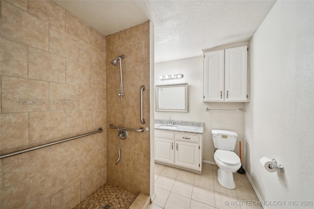 bathroom with a textured ceiling, tile patterned flooring, toilet, vanity, and a tile shower