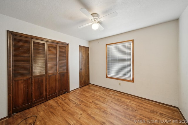 unfurnished bedroom featuring light wood finished floors, ceiling fan, and a textured ceiling